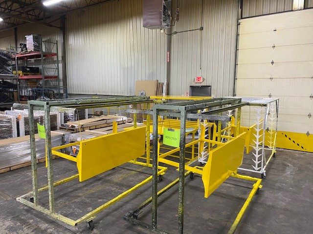 Industrial metal workstation with yellow safety barriers and metal framework inside a warehouse.