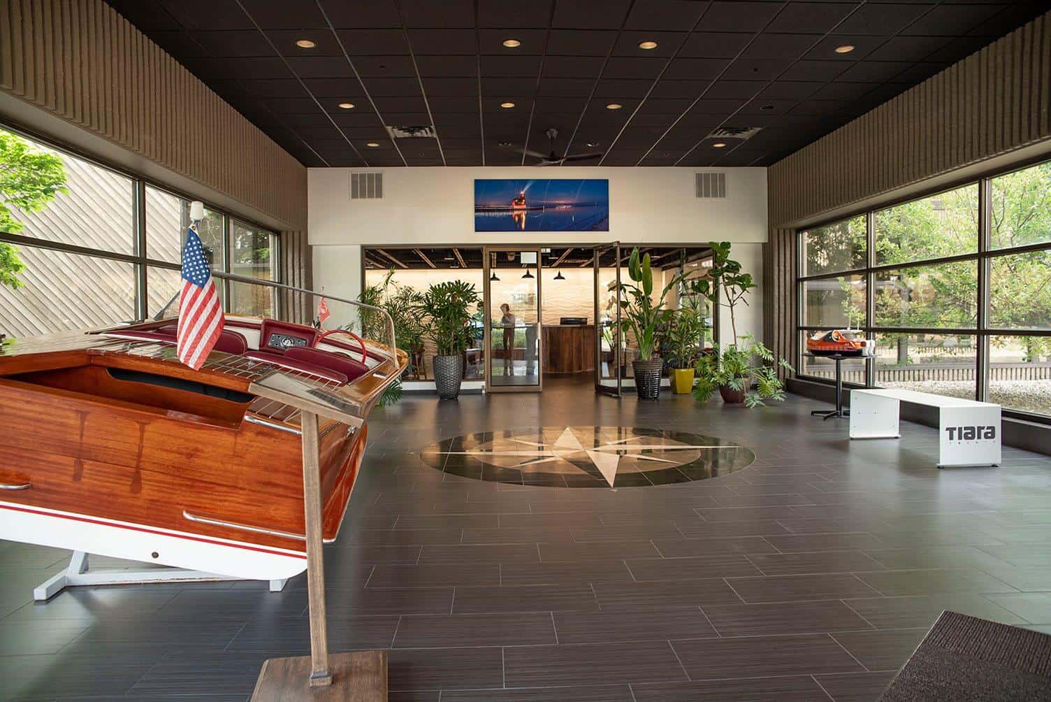 Modern office interior with boat display, plants, and large windows.