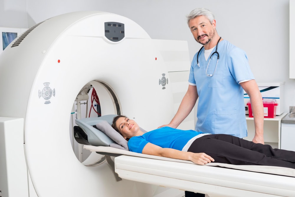 Erfahren Sie mehr über die Kosten gebrauchter CT-Geräte Bild: Ein Arzt hilft einer Patientin während einer CT-Untersuchung