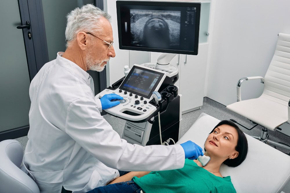 Ein Arzt macht einen Ultraschall an der Schilddrüse einer Patientin.