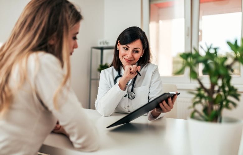 Patientin während der Patientenaufklärung mit Ärztin, die einen Aufklärungsbogen erklärt