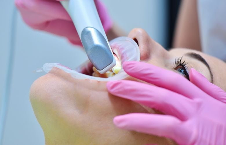 Zahnarzt scannt Patientenzähne mit Intraoralscanner für digitale Abrechnung