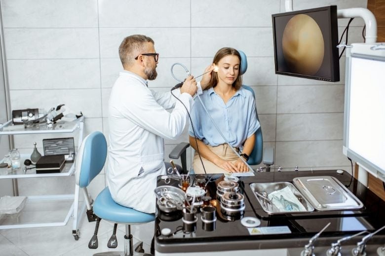 HNO-Arzt untersucht Ohr einer Patientin mit moderner Endoskopie-HNO-Behandlungseinheit in einer Facharztpraxis