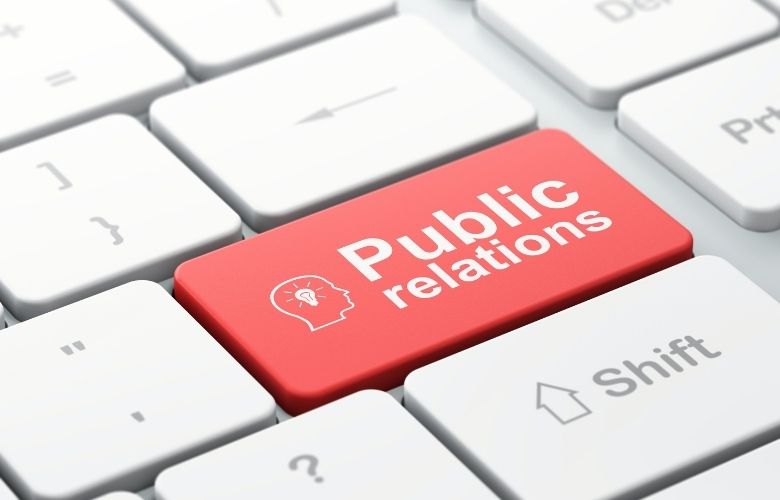Eine weiße Computertastatur mit einer auffälligen roten Taste, auf der Public Relations und ein Kopf-Symbol stehen.