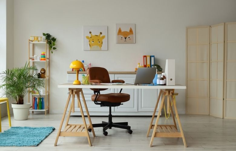 Moderner, heller Schreibtisch einer Kinderarztpraxis mit Laptop, Schreibtischlampe und freundlicher Dekoration.