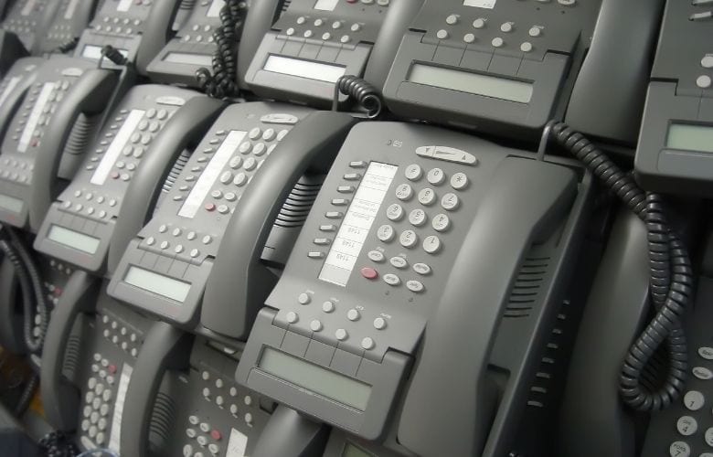 Sorgfältig aufgereihte graue Systemtelefone einer modernen Telefonanlage für die Arztpraxis.