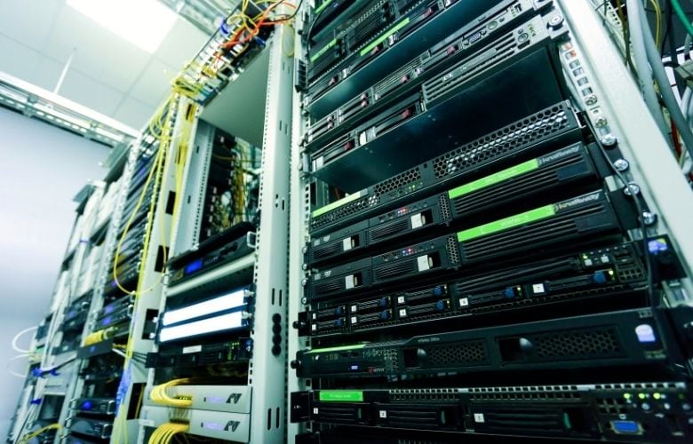 Offener Server-Schrank mit mehreren Server-Einheiten und gelben Netzwerkkabeln in einem Serverraum einer Arztpraxis.