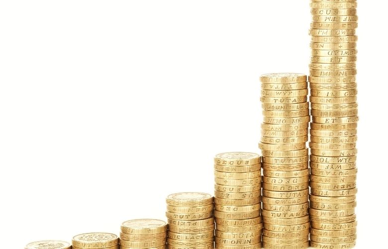 Aufsteigende Goldmünzen-Stapel, die eine Wachstumskurve bilden und steigenden Umsatz symbolisieren.