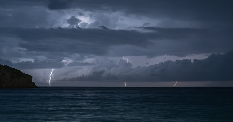 storm on the horizon with three lightning strikes