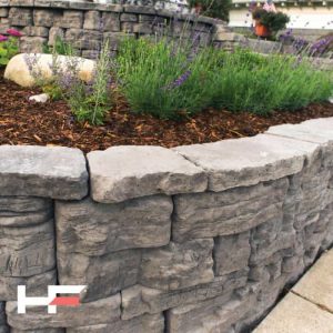 Stone garden wall with lavender and mulch for outdoor landscaping.