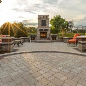 Outdoor patio with fireplace, seating, and basketball hoop at sunset.