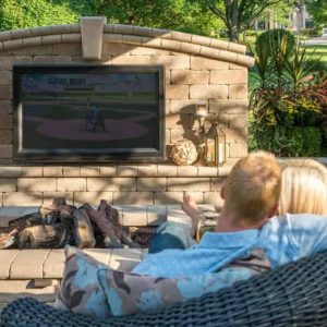 Outdoor fireplace with TV and cozy seating for relaxing and watching sports.