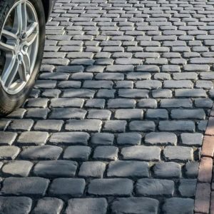 Cobblestone street with car wheel on the left side.