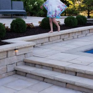 Elegant stone pool deck with garden landscaping and steps.