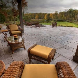 Outdoor patio with wicker chairs, ottomans, and scenic landscape view.