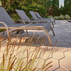 Outdoor lounge chairs on patio with garden scenery for relaxation.