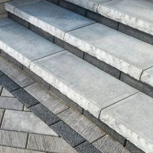 Elegant outdoor stone staircase with textured gray tiles and dark gray accents.
