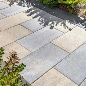 Outdoor stone paving with beige and gray tiles for garden pathways.