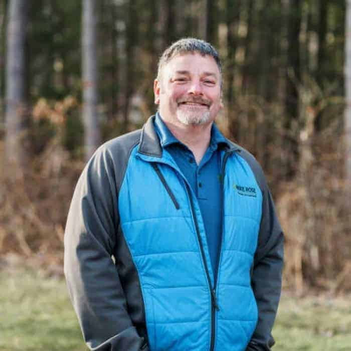 Staff member smiling outdoors in a blue jacket.