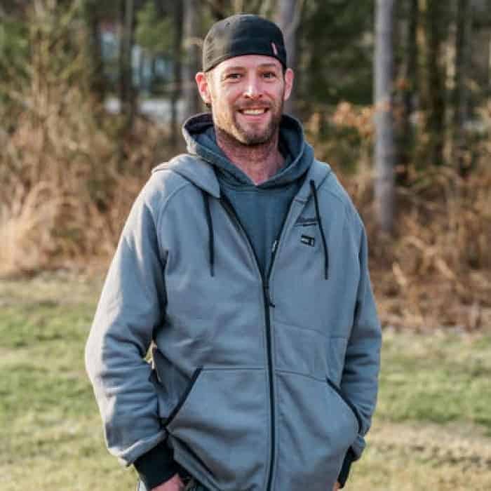 Man smiling outdoors in casual jacket for website branding.
