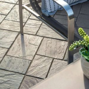Outdoor stone patio with furniture and potted plant for garden decor.