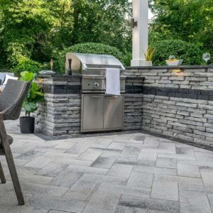 Outdoor kitchen with built-in grill and stone wall, perfect for entertaining.