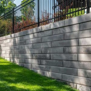Concrete retaining wall with black metal fence for garden boundary and privacy.