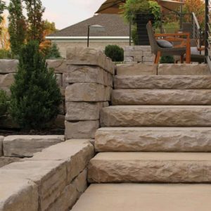 Stone staircase leading to a patio with outdoor furniture and lush greenery.