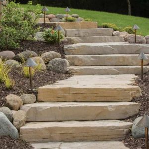 Outdoor stone staircase with landscape lighting for garden pathway illumination.