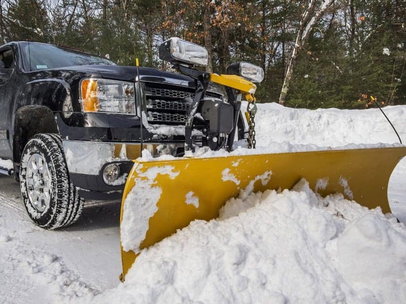 Snow plow truck clearing snow on a winter road in Muskegon County.