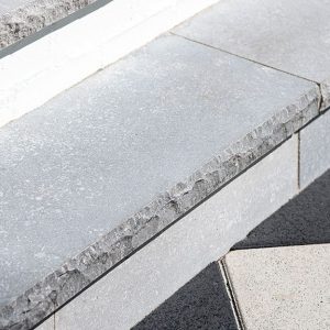Close-up of natural stone coping around a pool for durable outdoor design.