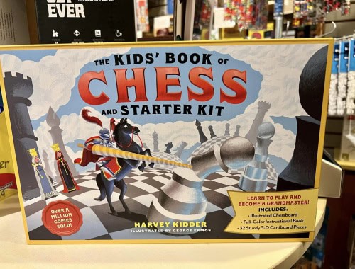 Children's chess starter kit with chessboard, pieces, and instructional book.
