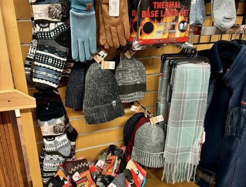 Winter gloves, hats, and scarves on a retail display.