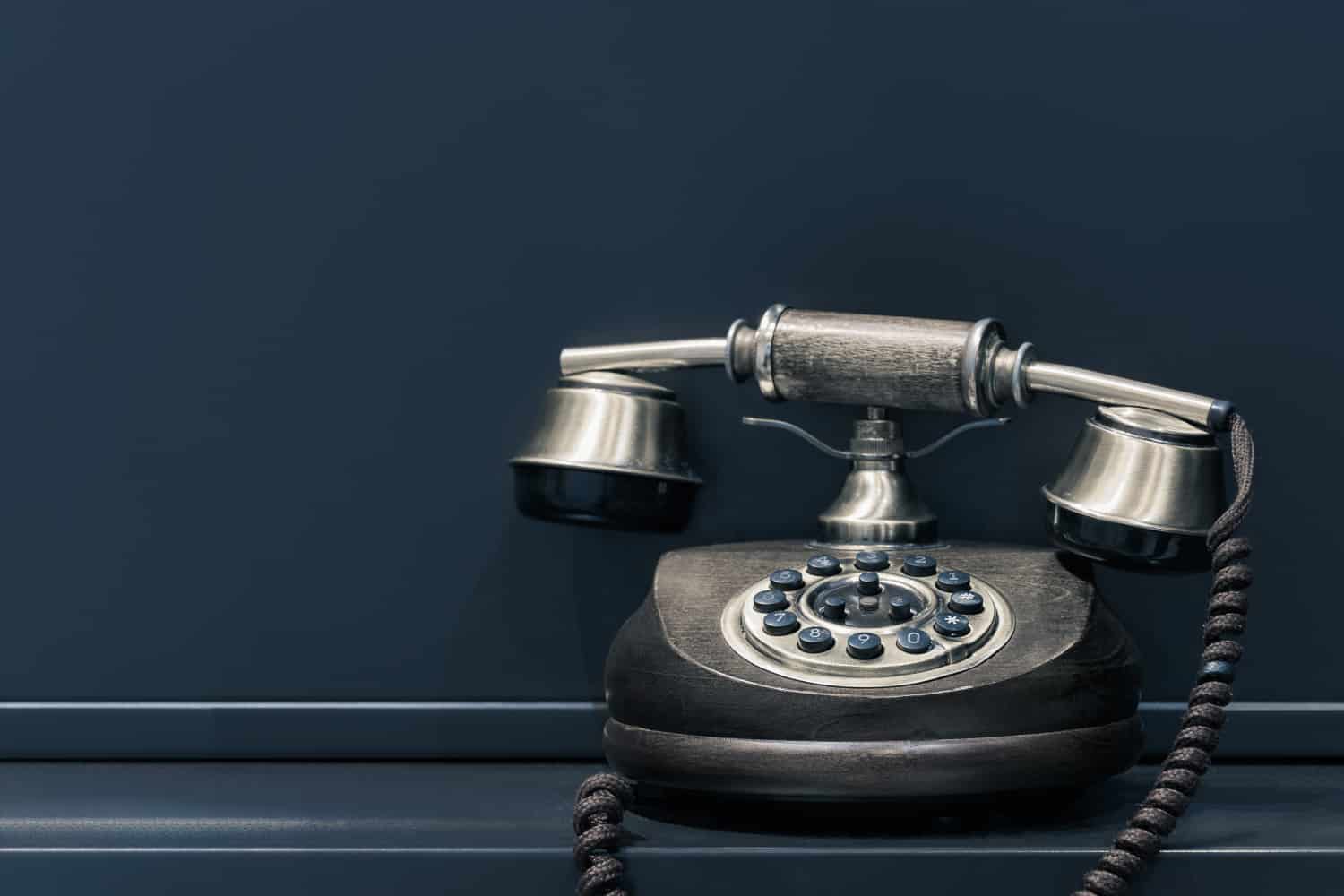 Vintage rotary dial telephone on a dark background.