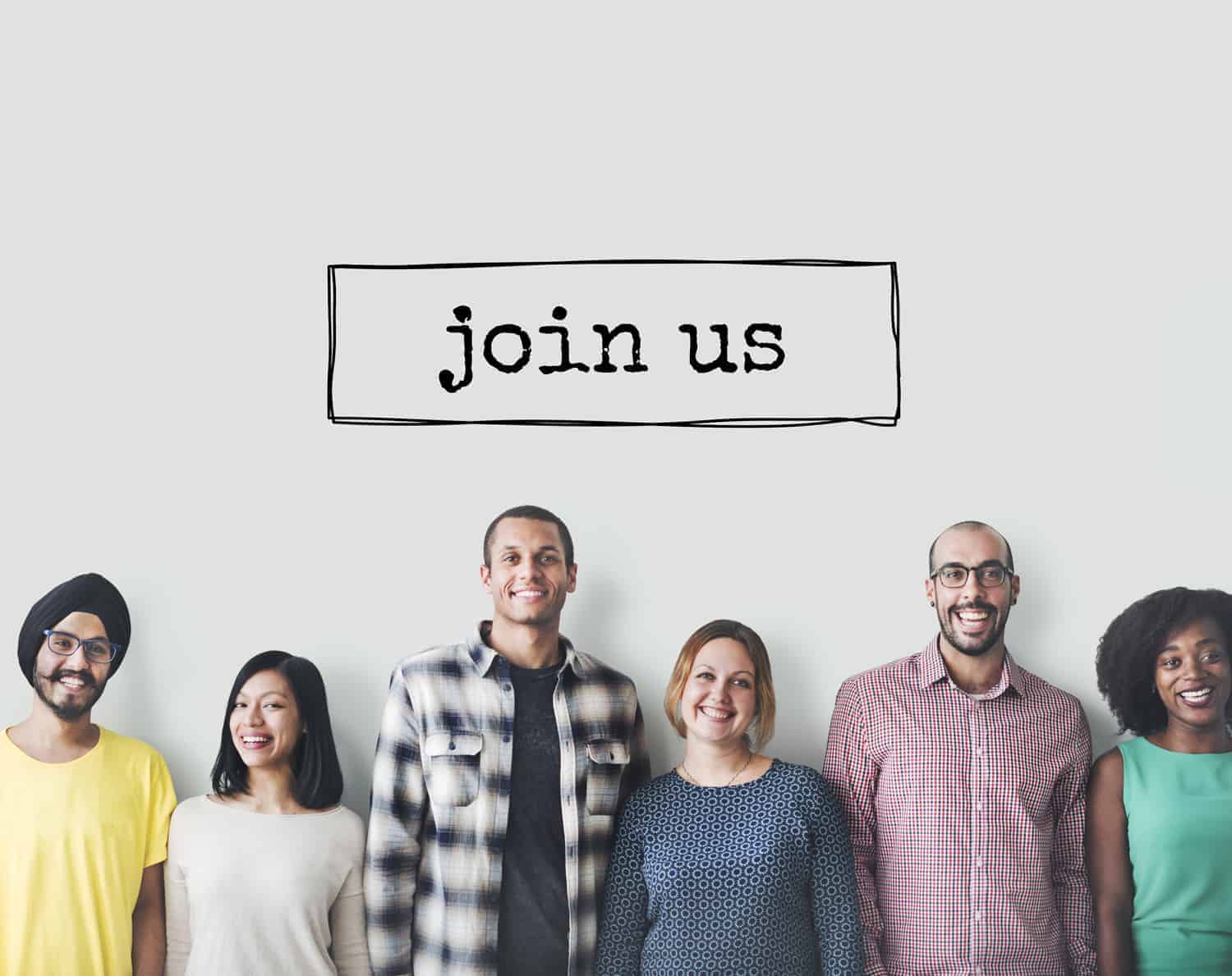 Diverse group of people smiling below a sign inviting others to "join our Local Heroes Wanted Campaign.