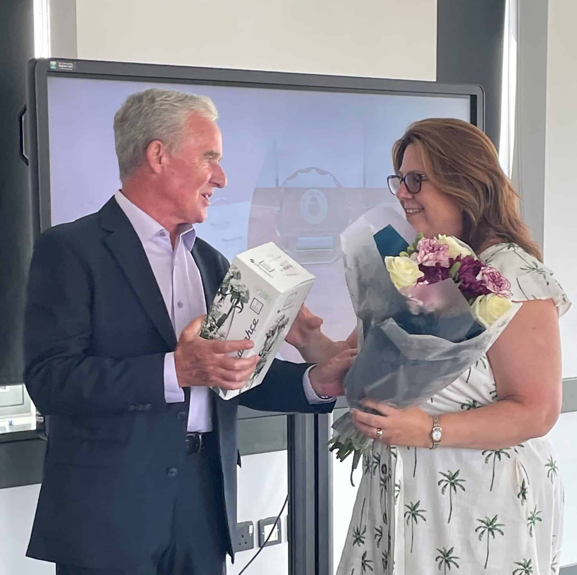 A cheerful exchange of gifts and smiles between two individuals in a professional setting.
