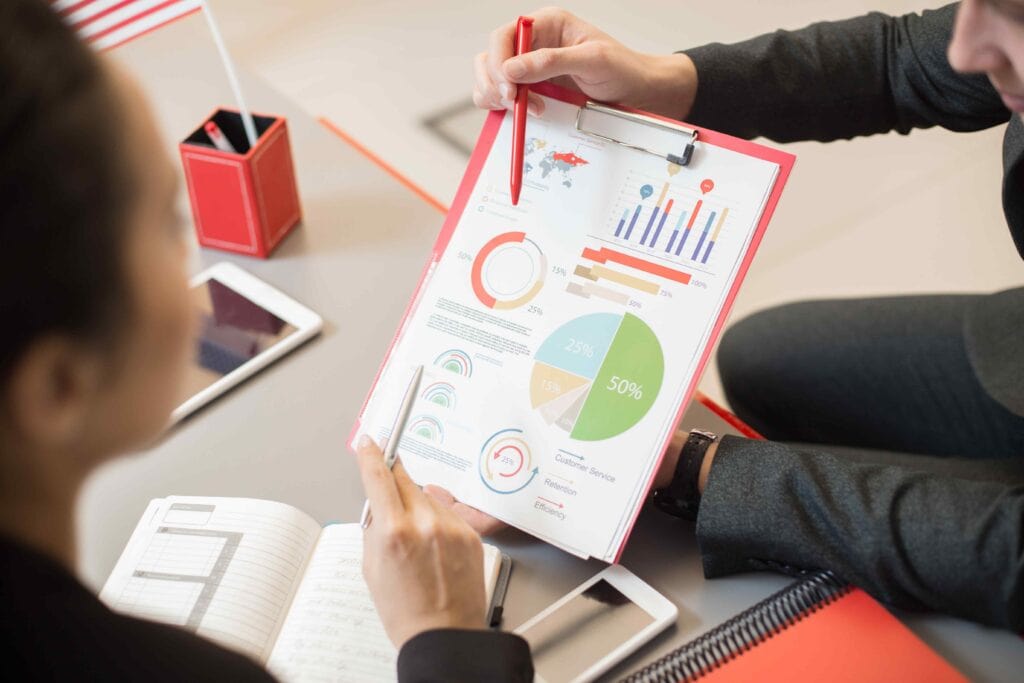Two individuals reviewing an SEO-related colorful data chart on a clipboard.