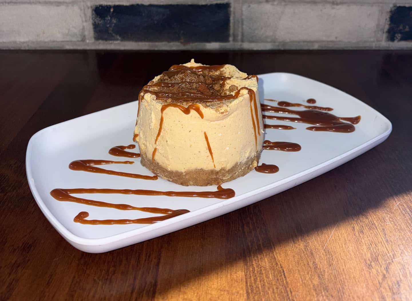 Delicious caramel cheesecake with chocolate drizzle on a white plate.