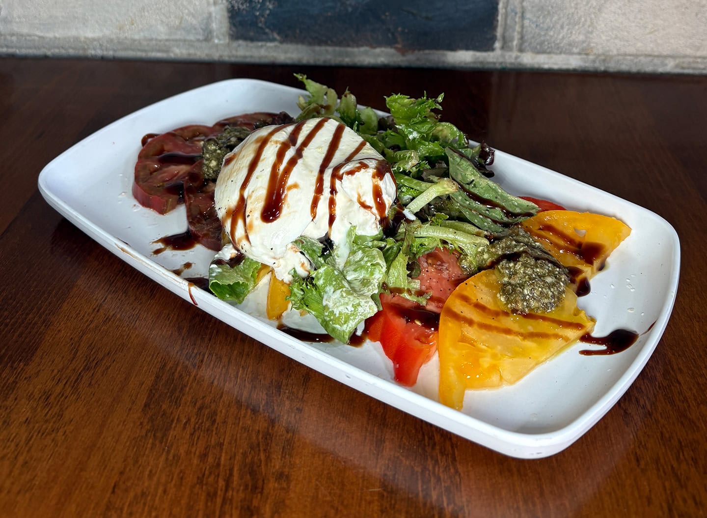 Fresh heirloom tomato and burrata salad with balsamic glaze and greens.