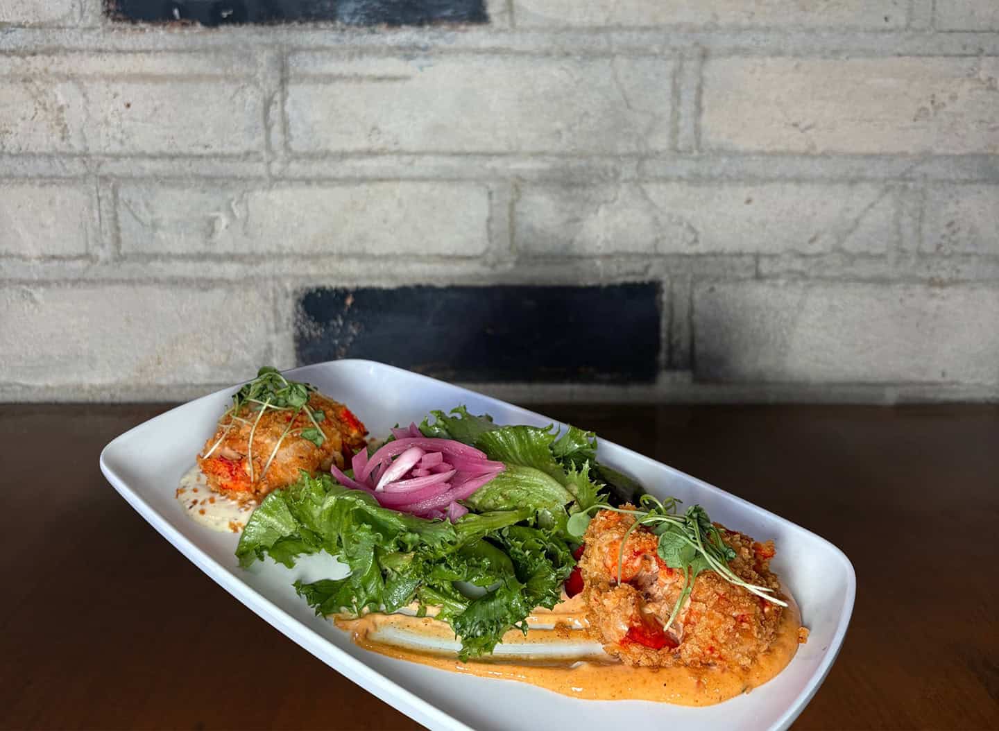 Delicious carrot cake with fresh greens and pickled onions on a white plate.