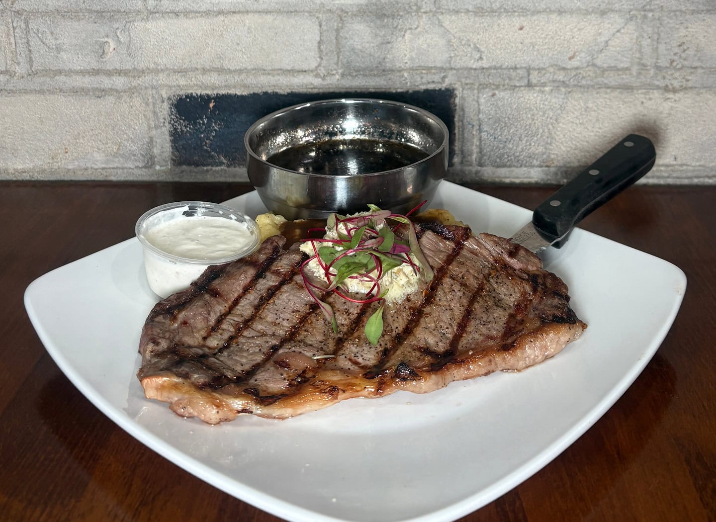 Grilled 14oz ribeye steak with sauce and onions.