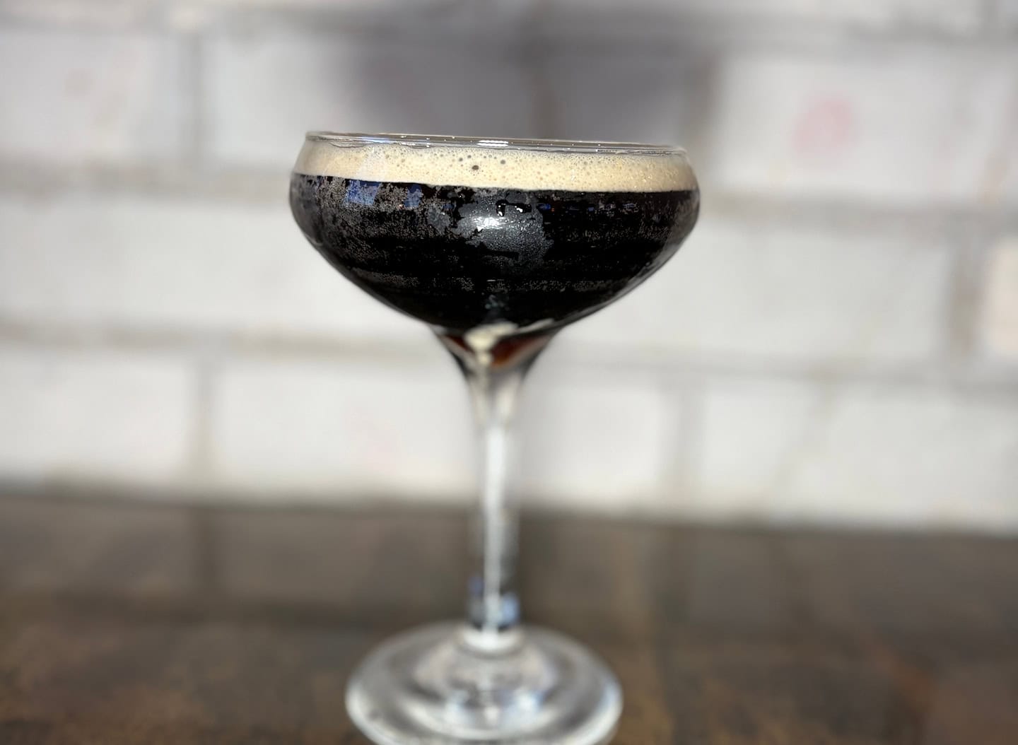 Rich dark beer served in a stylish coupe glass with a foamy head.