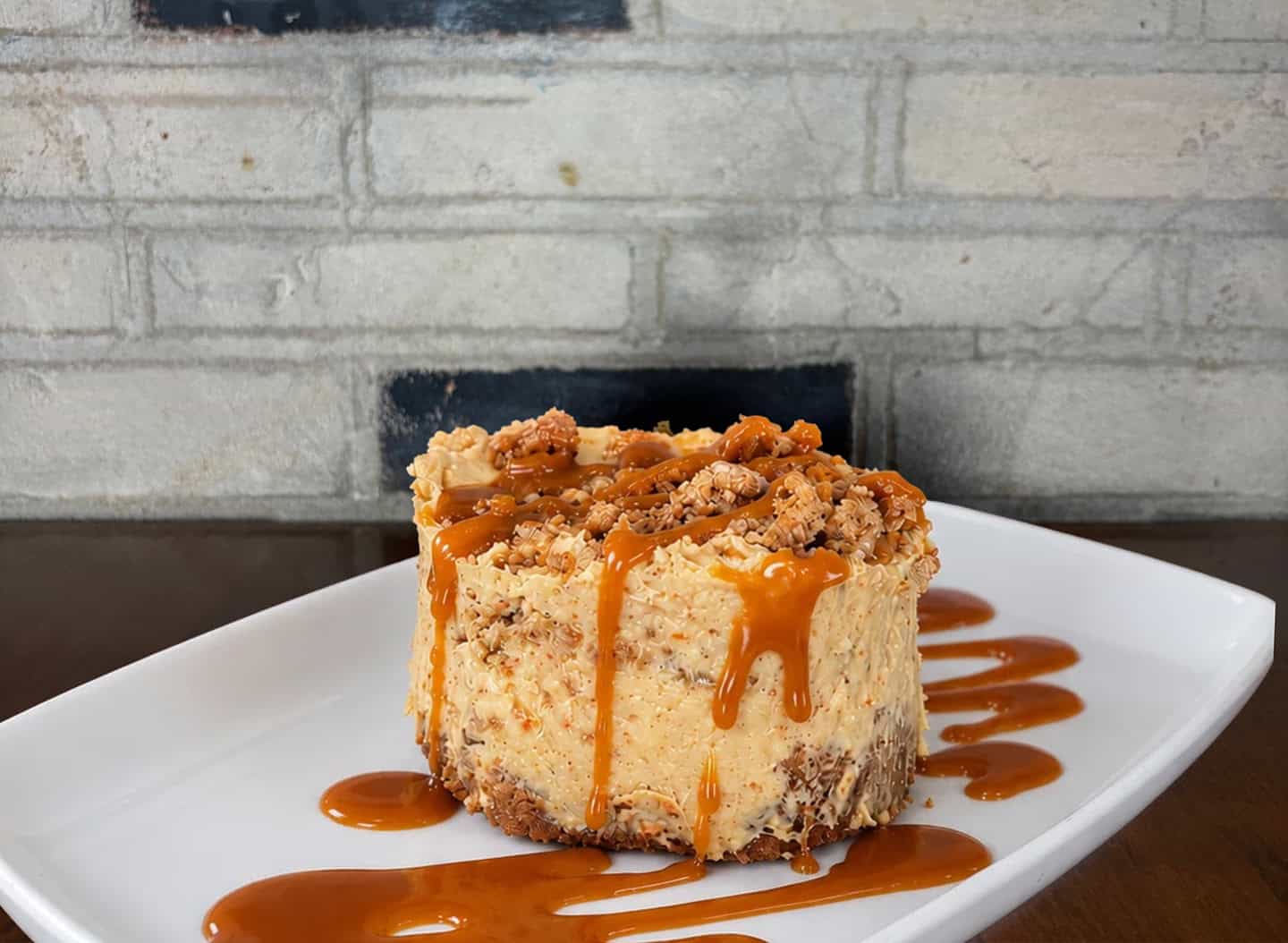 Delicious carrot cake with caramel drizzle and crumb topping on a white plate.