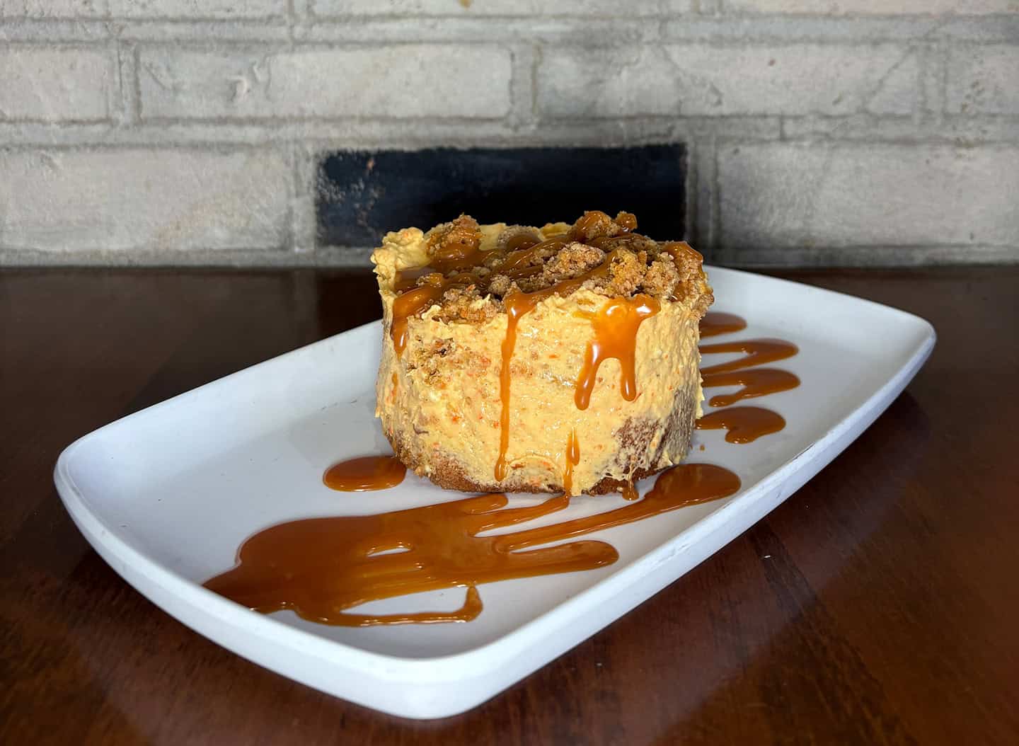 Delicious carrot cake slice with caramel drizzle on a white plate.