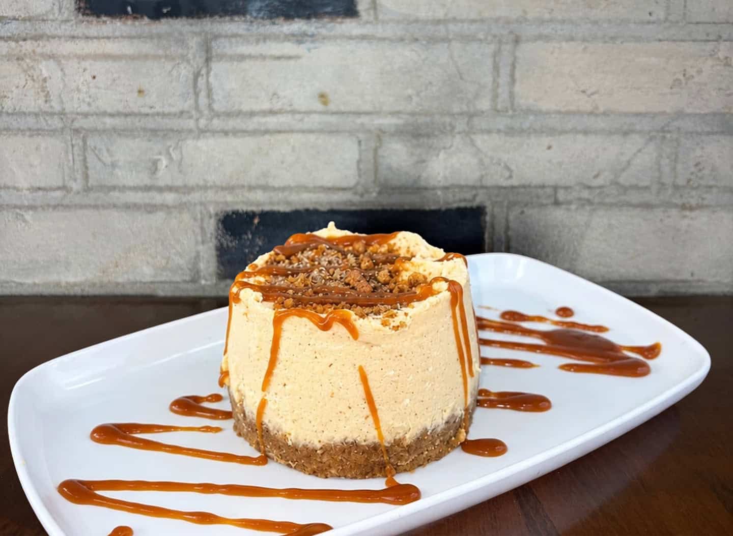 Delicious pumpkin cheesecake with caramel drizzle on a white plate.