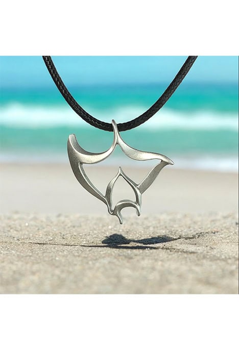 Un pendentif en forme de raie manta évoque l'élégance marine sur une plage ensoleillée, parfait pour les passionnés de plo...