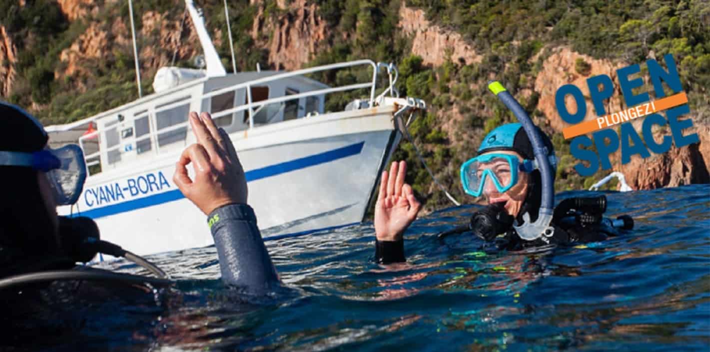 Deux plongeurs échangent des signaux près d'un bateau, prêts à explorer les merveilles sous-marines de la Méditerranée.