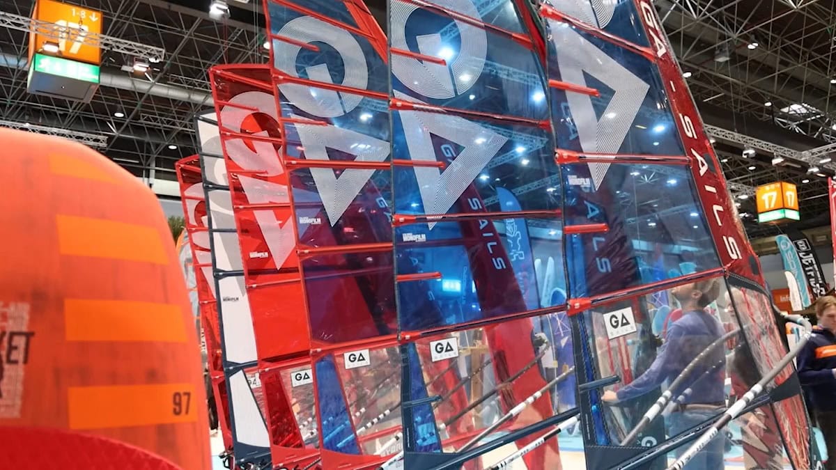 Voiles colorées et équipements de sports nautiques exposés lors d'un salon maritime.