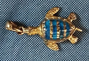 Un pendentif tortue doré et bleu évoque la beauté des récifs coralliens, symbole de protection marine.
