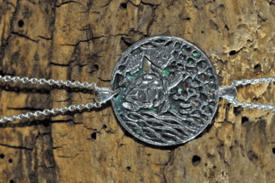 _DBM9876bis Bijou en argent représentant une tortue marine sur fond aquatique, symbole de la vie sous-marine.